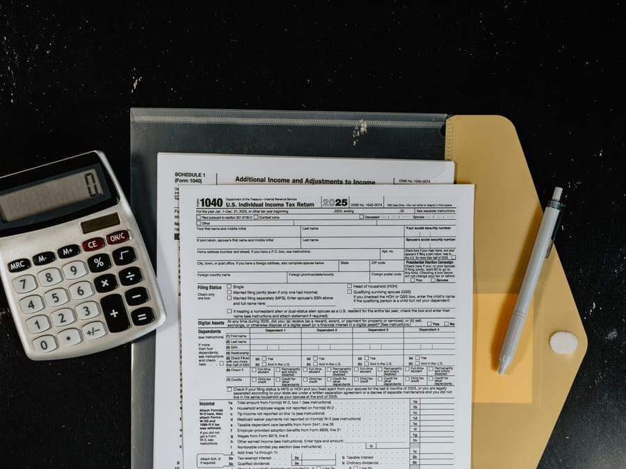 Calculator and tax forms on a dark desk surface