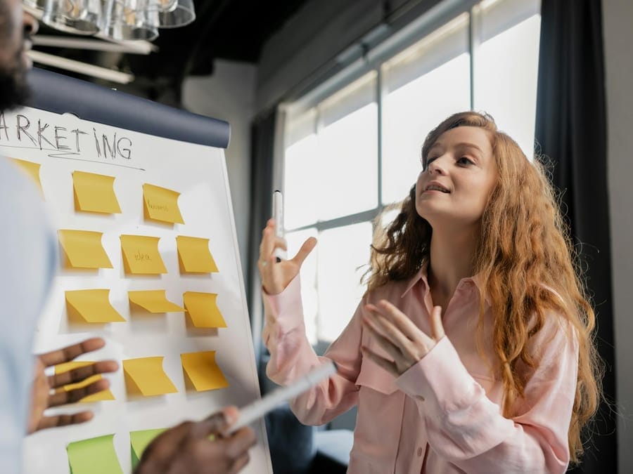 Business team discussing marketing strategy with sticky notes on a board