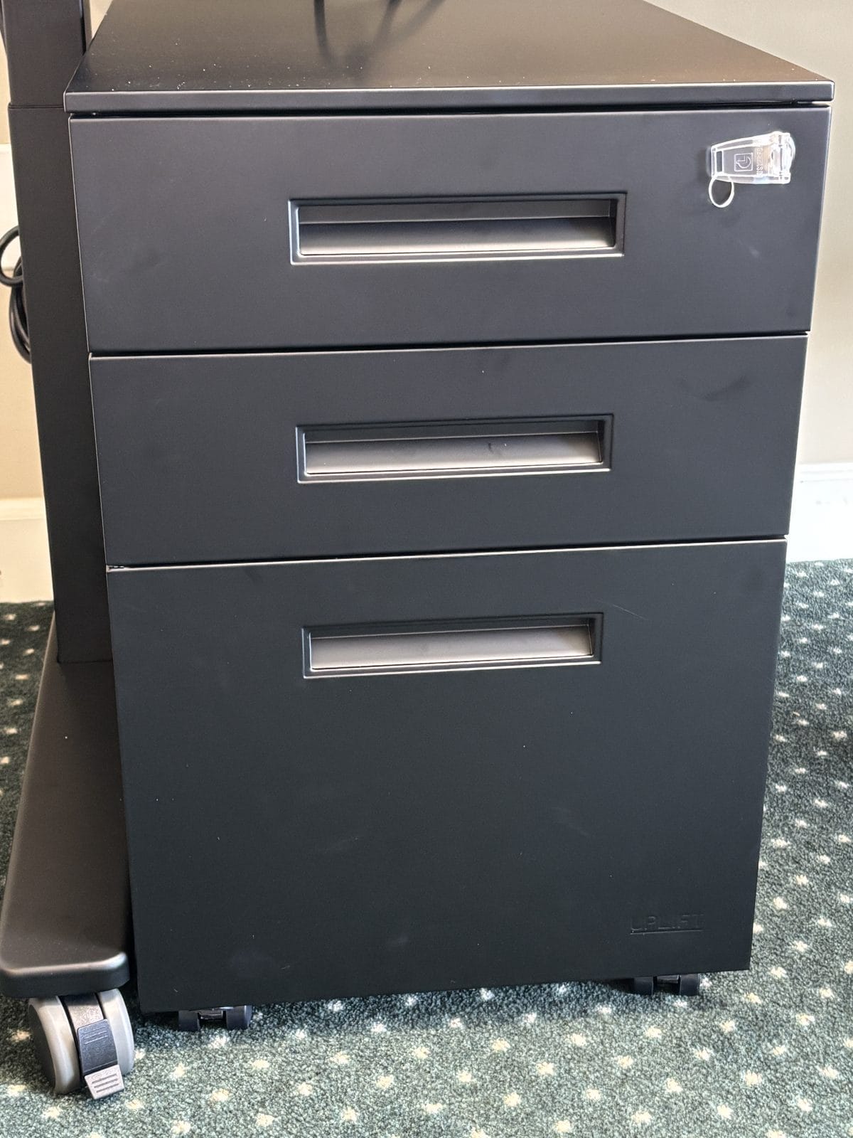 Close-up of the black 3-Drawer Square File Cabinet showing the single top-drawer lock and a front caster wheel.