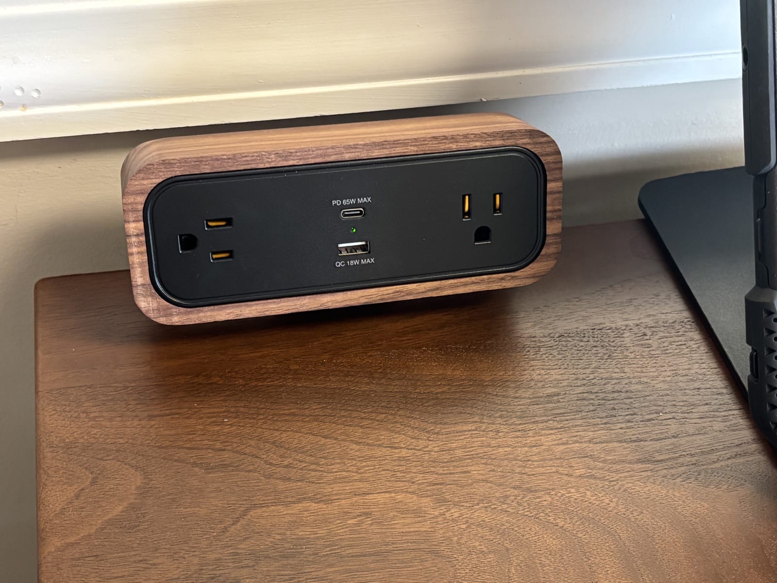 UPLIFT DuoMount power strip with a walnut accent finish sitting on the desktop, with two outlets and a USB-C and USB-A port.