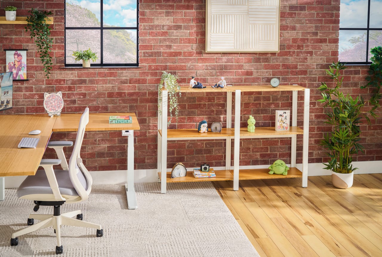 UPLIFT product photo of a double short Sequence Shelving layout with a white frame and light wood-tone shelves against a brick wall, next to an L-shaped standing desk.